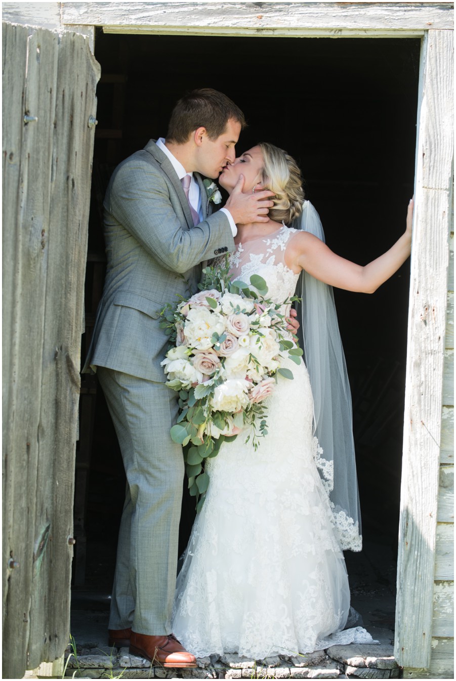 Wedding couple poses in barn doorway at The Oaks by Melissa Grimes-Guy Photography